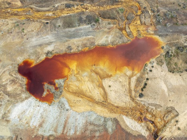 Deep orange-red hues in the water of a pool in the mineral-rich area of the Rio Tinto mines. The colour is caused by oxidised iron minerals. Aerial view. Drone shot. Huelva province, Andalusia, Spain