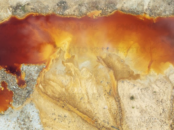 Deep orange-red hues in the water of a pool in the mineral-rich area of the Rio Tinto mines. The colour is caused by oxidised iron minerals. Aerial view. Drone shot. Huelva province, Andalusia, Spain