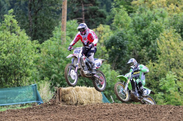Motocross, Rudersberg, Baden-Württemberg, Germany, Europe, Two motocross riders jump over a mound of earth, trees in the background, Rudersberg motocross