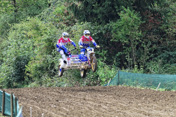 Motocross, Rudersberg, Baden-Württemberg, Germany, Europe, Two riders with sidecars jump over a dirt track surrounded by green trees, Rudersberg motocross