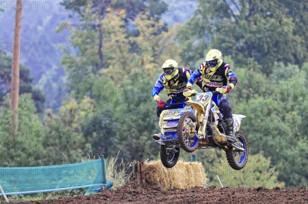 Motocross, Rudersberg, Baden-Württemberg, Germany, Europe, Motocross duo with sidecar jumps into the air in front of a wooded backdrop, Rudersberg motocross