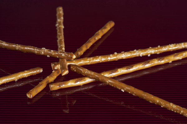Closeup of some salt sticks on dark red striped glossy ground