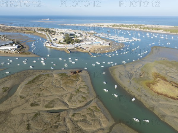 Network of channels and streams at low tide and the fishing village of Sancti Petri at the Atlantic Ocean. In the marshland of the Bahía de Cádiz Nature Reserve. Aerial view.. Drone shot. Cádiz province, Andalusia, Spain