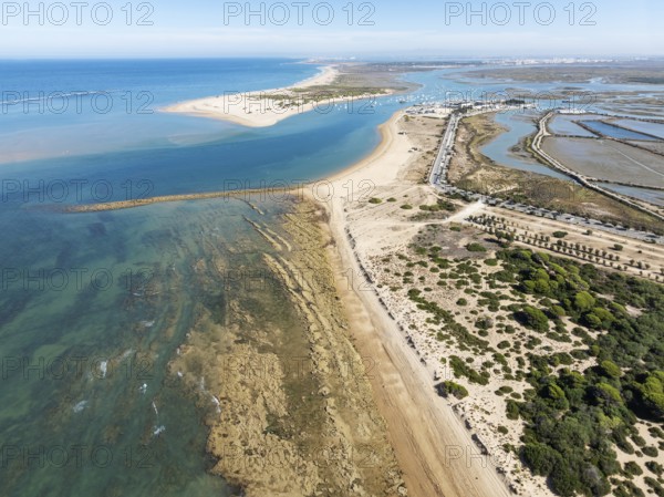 Aerial view of the Atlantic Coast with the fishing village of Sancti Petri, the large sandbar of Punta del Boquerón and the surrounding marshes at low tide. In the distance the town of San Fernando. Drone shot. Bahía de Cádiz Nature Reserve. Cádiz province, Andalusia, Spain