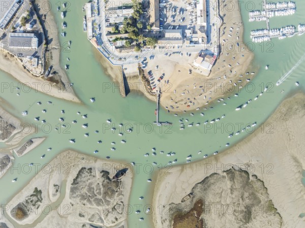 Fishing boats at low tide at the fishing village of Sancti Petri. In the marshland of the Bahía de Cádiz Nature Reserve. Aerial view.. Drone shot. Cádiz province, Andalusia, Spain