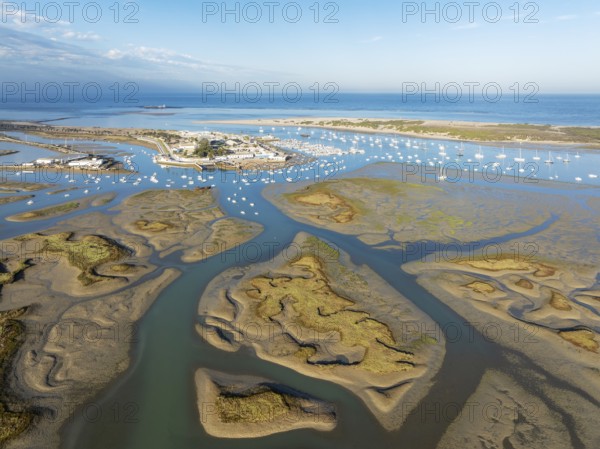 Network of channels and streams at low tide and the fishing village of Sancti Petri at the Atlantic Ocean. In the marshland of the Bahía de Cádiz Nature Reserve. Aerial view.. Drone shot. Cádiz province, Andalusia, Spain