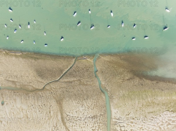 Sports and fishing boats at low tide near the fishing village of Sancti Petri. In the marshland of the Bahía de Cádiz Nature Reserve. Aerial view.. Drone shot. Cádiz province, Andalusia, Spain