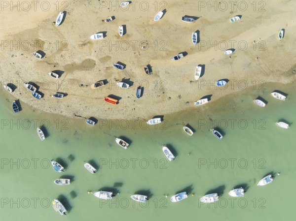 Fishing boats at low tide at the fishing village of Sancti Petri. In the marshland of the Bahía de Cádiz Nature Reserve. Aerial view.. Drone shot. Cádiz province, Andalusia, Spain
