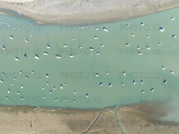 Sports and fishing boats at low tide near the fishing village of Sancti Petri. In the marshland of the Bahía de Cádiz Nature Reserve. Aerial view.. Drone shot. Cádiz province, Andalusia, Spain