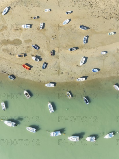 Fishing boats at low tide at the fishing village of Sancti Petri. In the marshland of the Bahía de Cádiz Nature Reserve. Aerial view.. Drone shot. Cádiz province, Andalusia, Spain