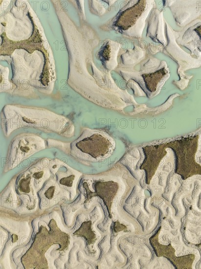 Network of channels and streams at low tide. In the marshland of the Bahía de Cádiz Nature Reserve. Aerial view. Drone shot. Cádiz province, Andalusia, Spain