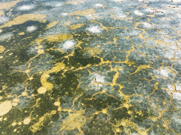 Abstract patterns in the shallow water of a saline pond in the marshland of the Bahía de Cádiz Nature Reserve. Aerial view. Drone shot. Cádiz province, Andalusia, Spain