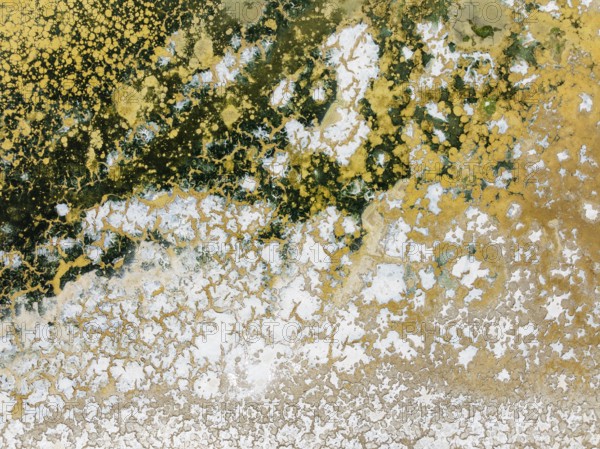Abstract patterns in the shallow water of a saline pond in the marshland of the Bahía de Cádiz Nature Reserve. Aerial view. Drone shot. Cádiz province, Andalusia, Spain