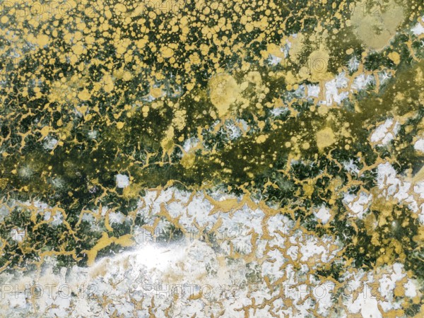 Abstract patterns in the shallow water of a saline pond in the marshland of the Bahía de Cádiz Nature Reserve. Aerial view. Drone shot. Cádiz province, Andalusia, Spain
