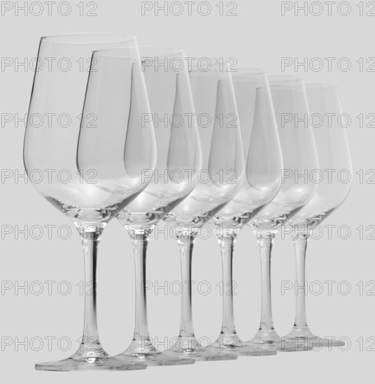 Some clean and empty wine glasses standing in a row in light grey back