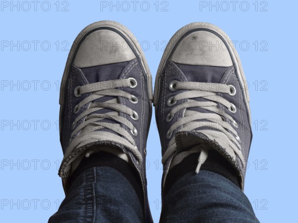 Some feet with sneakers in front of blue sky