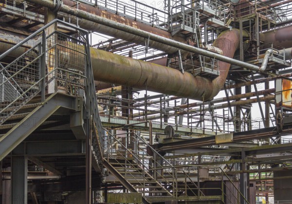Weathered rundown industrial scenery with old corroded steel girders, stairs and metal tubes