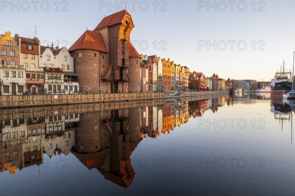 Waterfront promenade with reflection at sunrise in the Old Town, Brama Zuraw crane gate, Motlawa River, Gdansk, Gdansk, Poland