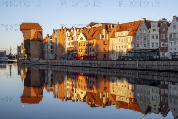 Waterfront promenade with reflection at sunrise in the Old Town, Brama Zuraw crane gate, Motlawa River, Gdansk, Gdansk, Poland