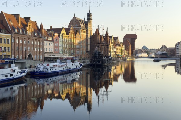 Waterfront promenade with reflection at sunrise in the Old Town, Motlawa River, Gdansk, Poland