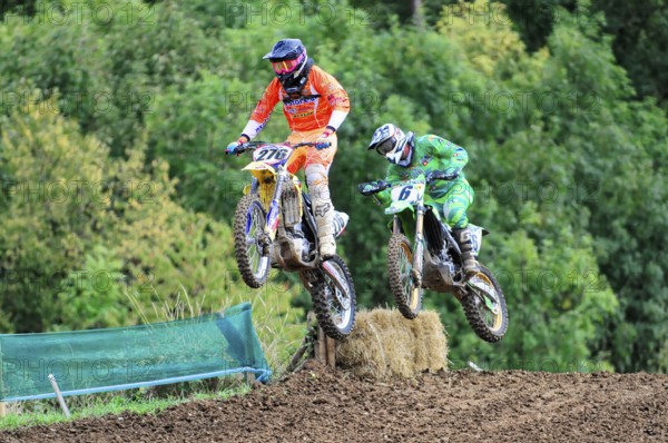 Motocross, Rudersberg, Baden-Württemberg, Germany, Europe, Two motocross riders jump over a ramp in a wooded area, Rudersberg motocross