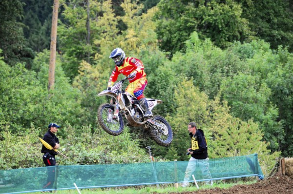 Motocross, Rudersberg, Baden-Württemberg, Germany, Europe, A rider in red protective clothing jumps over a barrier in the terrain on his motocross bike, Rudersberg motocross