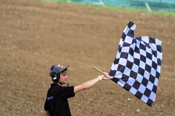 Motocross, Rudersberg, Baden-Württemberg, Germany, Europe, Man waving a black and white chequered flag on a dry field, Rudersberg motocross