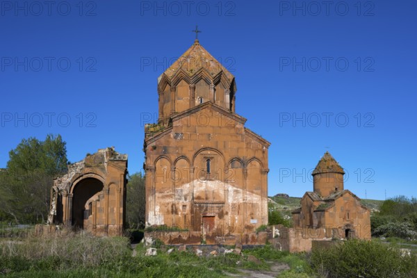 Historic brick church under a clear sky, surrounded by vegetation, cross-domed church, Marmashen Monastery, Marmashen Vank, Shirak Province, Armenia