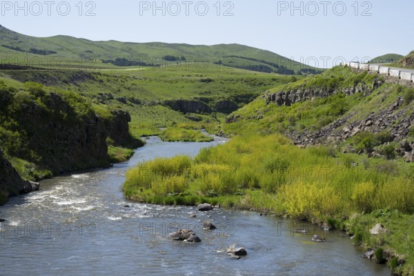 A river runs along green meadows and hills with a road on the right, Achuryan River, Akhuryan, near Jradzor, Shirak Province, Armenia