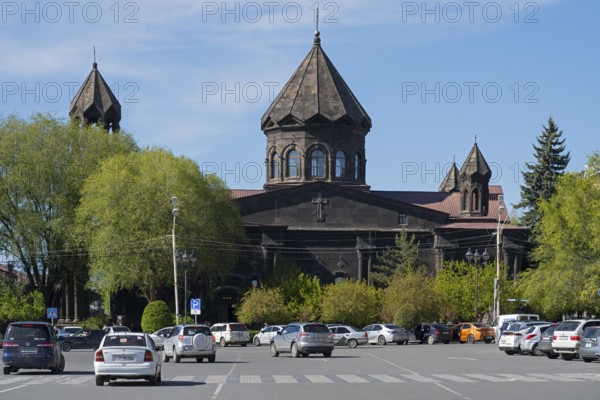 A black church with old architecture and parked cars in a green setting, Cathedral of the Holy Mother of God, Our Lady of the Seven Wounds, Gyumri, Gyumri, Shirak Province, Armenia