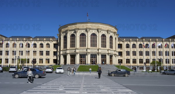 A large town hall with a classical façade, people and cars under a clear sky, Gyumri, Gyumri, Shirak Province, Armenia