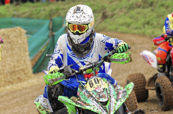 Motocross, Rudersberg, Baden-Württemberg, Germany, Europe, A heavily soiled quad rider in a blue and green outfit on a muddy track, Rudersberg Motocross