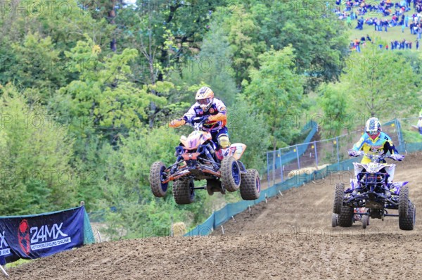 Motocross, Rudersberg, Baden-Württemberg, Germany, Europe, A quad bike rider jumps over a track surrounded by forest and spectators during a race, Rudersberg Motocross