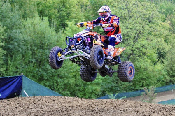 Motocross, Rudersberg, Baden-Württemberg, Germany, Europe, A quad bike rider takes off into the air during a motocross race, surrounded by green trees, Rudersberg motocross