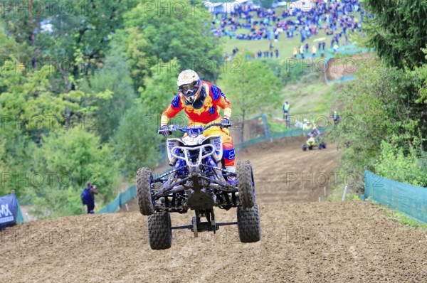 Motocross, Rudersberg, Baden-Württemberg, Germany, Europe, A quad bike rider jumps over a track, followed by spectators in the background, Rudersberg Motocross