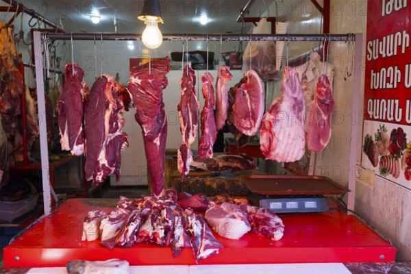 An illuminated market stall with raw meat and hangers, meat hanging open in the shop, Gyumri, Gyumri, Shirak province, Armenia