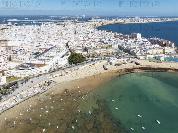 The town of Cádiz with the old quarter in the foreground. Prominent the Caleta beach, the old Balneario de la Palma and the fishing boats at low tide. Aerial view. Drone shot. Cádiz province, Andalusia, Spain