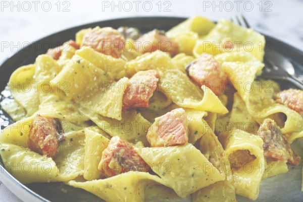 Papardelle pasta, in creamy sauce with salmon, natural light, lifestyle, homemade, on a gray background, no people