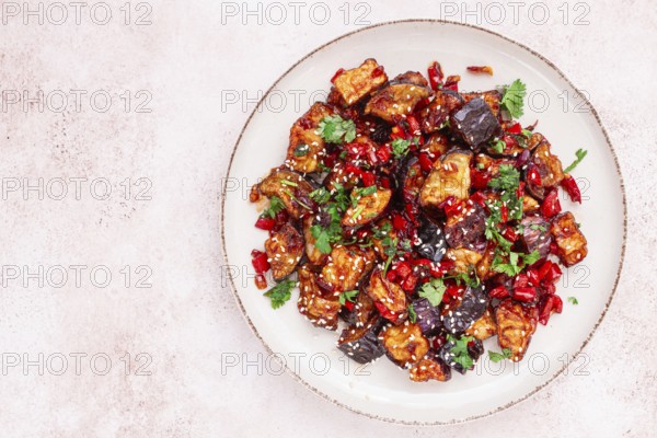 Fried eggplant, Chinese style, in sweet and sour sauce, with pepper and sesame seeds. on a white plate