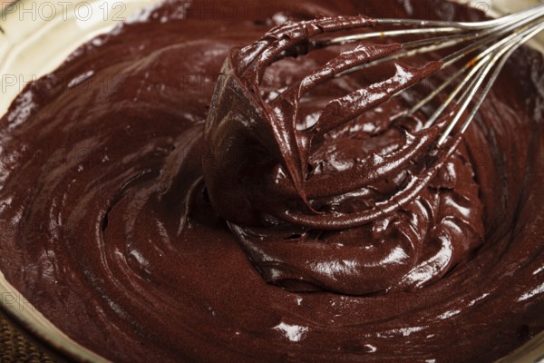 A bowl of chocolate dough, a whisk for whipping, baking, structure and consistency, homemade, top view, no people