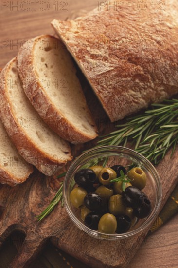 Sliced ciabatta, on a chopping board, with rosemary and olives, Italian bread, close-up, Italian cuisine, breakfast, no people