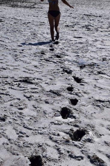 Woman walking along the dry bottom of a salt lake, rear view. Taman, Krasnodar Krai, Russia