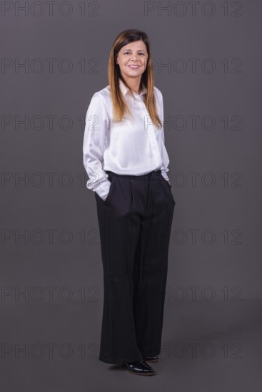 Elegant senior businesswoman smiling with her hands in her pockets