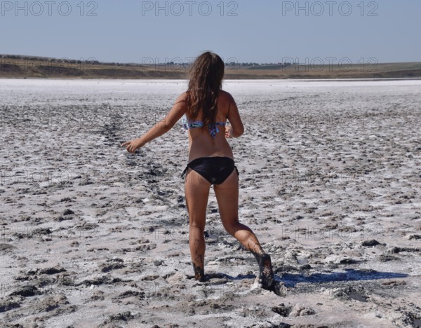 Woman walking along the dry bottom of a salt lake, rear view. Taman, Krasnodar Krai, Russia