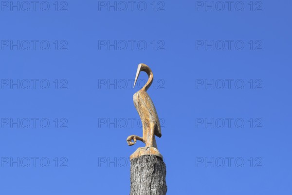 Figure of crane on the stump of a tree against the blue sky. Taman, Krasnodar Krai, Russia