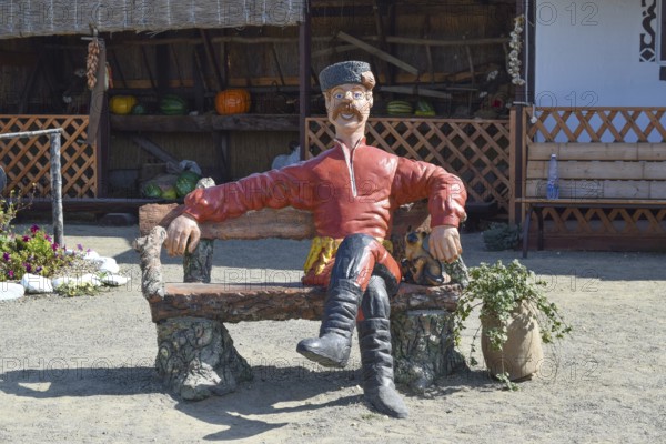 Statue in Cossack fur hat sitting on a bench with a cat. Taman, Krasnodar Krai, Russia