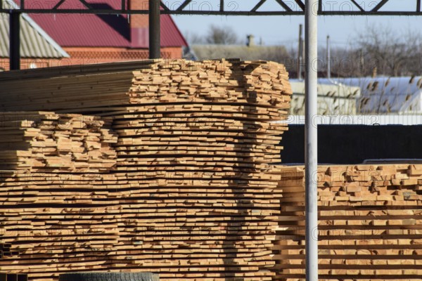 Warehouse of building materials, wood planks stacked under a canopy. Atyrau, Kazakhstan