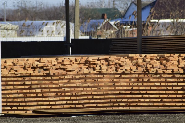 Warehouse of building materials, wood planks stacked under a canopy. Atyrau, Kazakhstan
