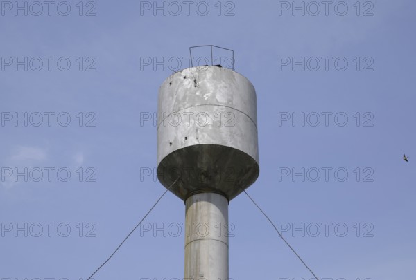 Silver Water Tower among green grass and trees. Atyrau, Kazakhstan
