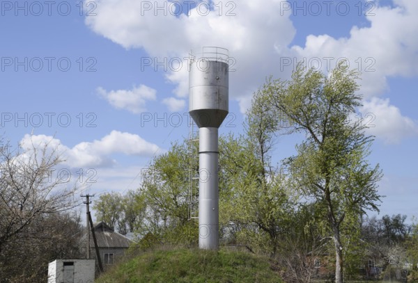 Silver Water Tower among green grass and trees. Atyrau, Kazakhstan